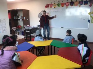 Jovem em sala de aula ministrando aula para crianças